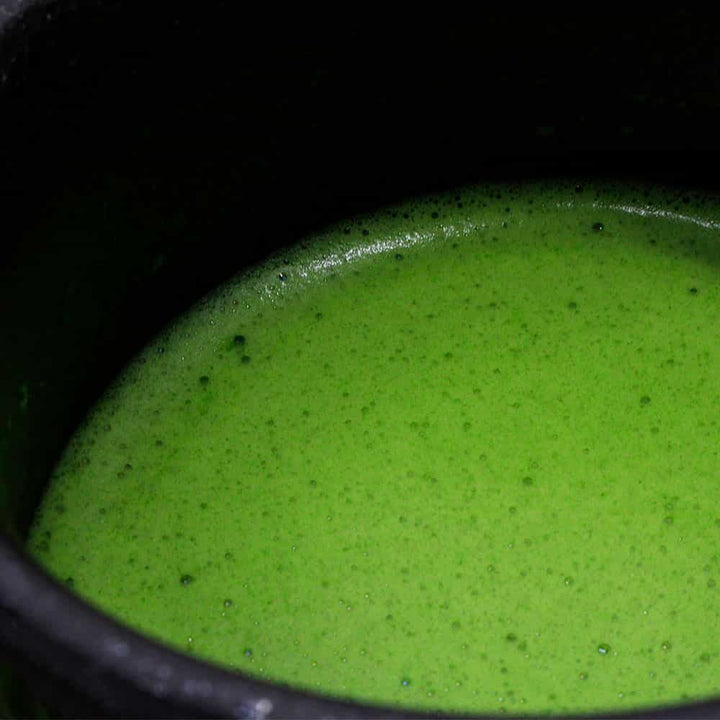 Freshly whisked matcha in a dark bowl.